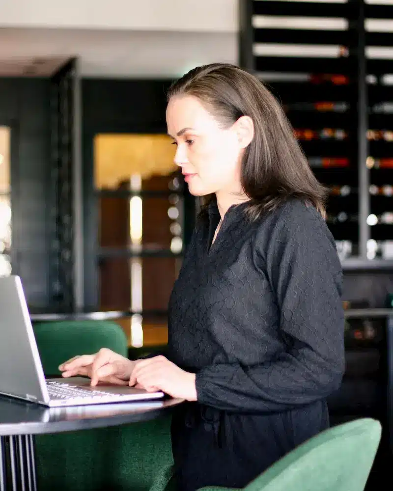 Linda Visser werkt geconcentreerd aan laptop in moderne kantooromgeving